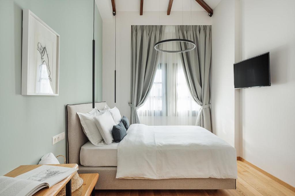 约阿尼纳Petrou Suites的白色的卧室设有床和窗户