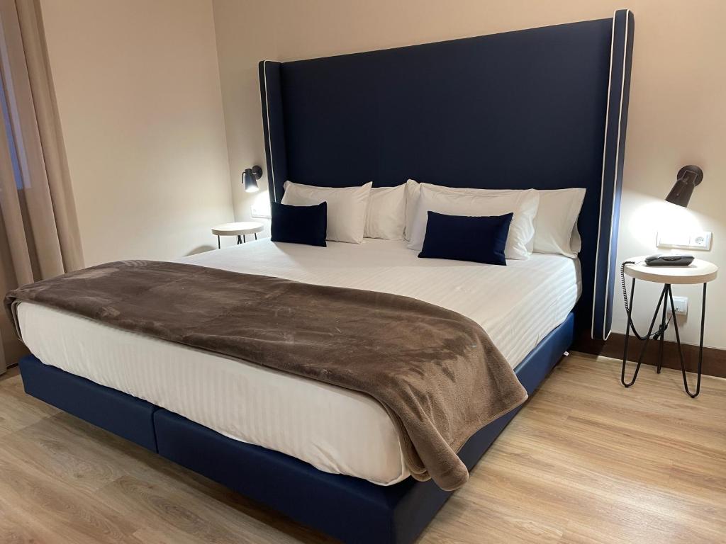 托莱多玛丽亚克里斯蒂娜酒店的一间卧室配有一张大床和蓝色床头板