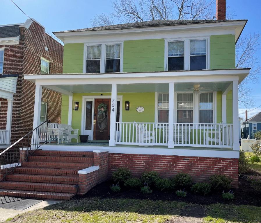 开普查尔斯Key Lime Cottage steps from Cape Charles Beach的绿色房子,设有白色门廊和楼梯