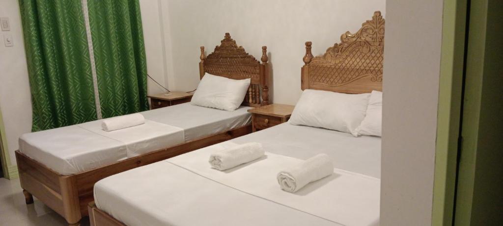 圣维森特Rabang Traveller's Inn的绿窗帘间内的两张单人床