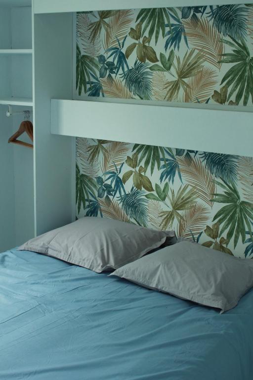 珀蒂蒂勒Les bungalows du chateau d'Ô的一间卧室配有一张蓝色的床和热带壁纸