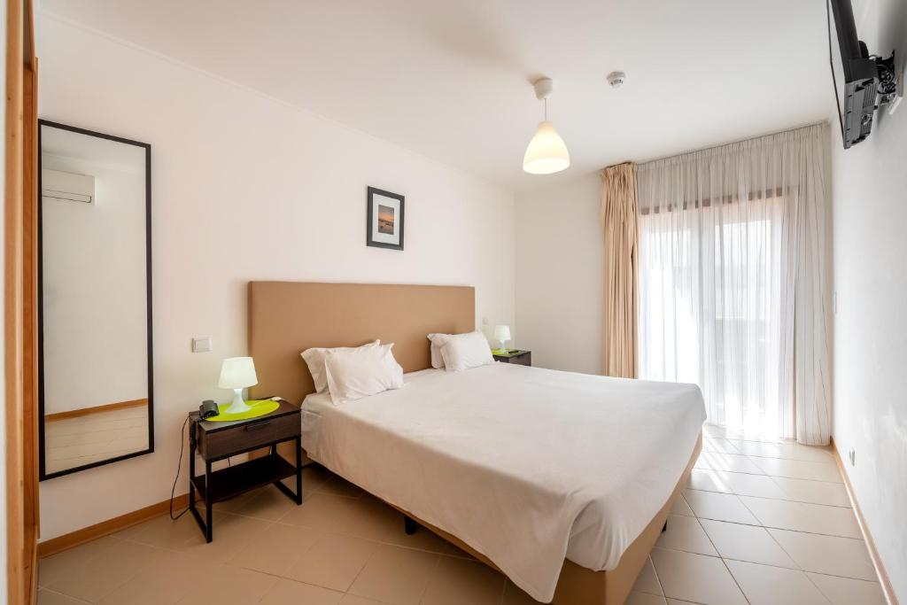 波尔蒂芒罗沙米兰特公寓的卧室设有一张白色大床和一扇窗户。