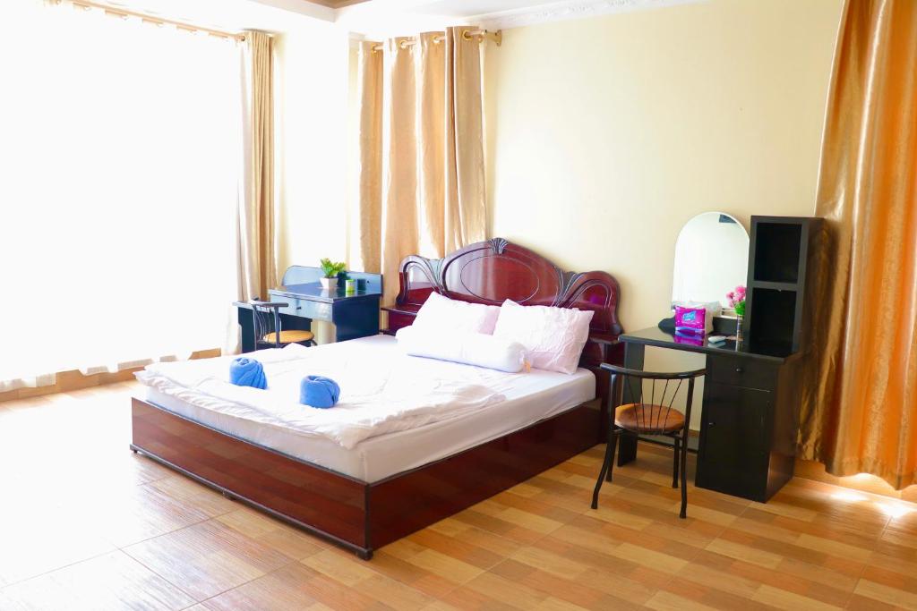 金边Gvai Apartment的一间卧室配有一张床、一张书桌和一台电视