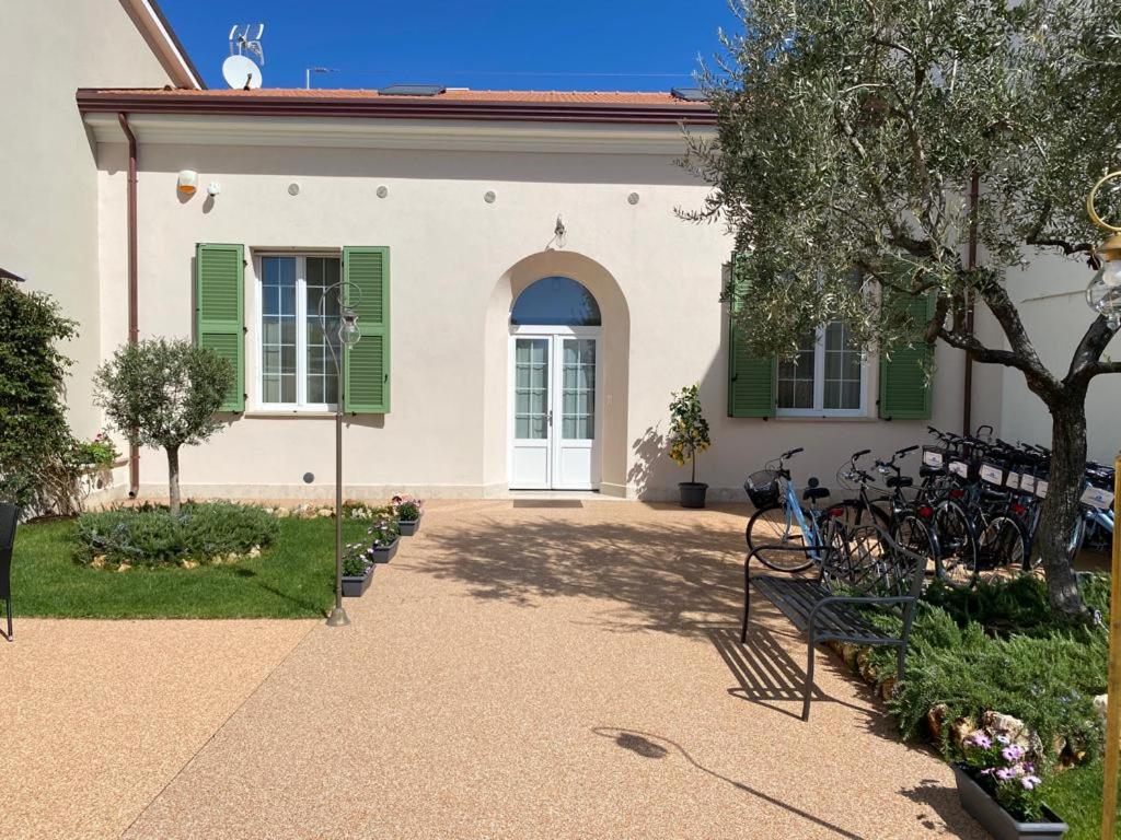 马瑞纳迪卡拉拉Villino Micol camere a due passi dal mare的一座带绿色百叶窗的房子,前面设有长凳