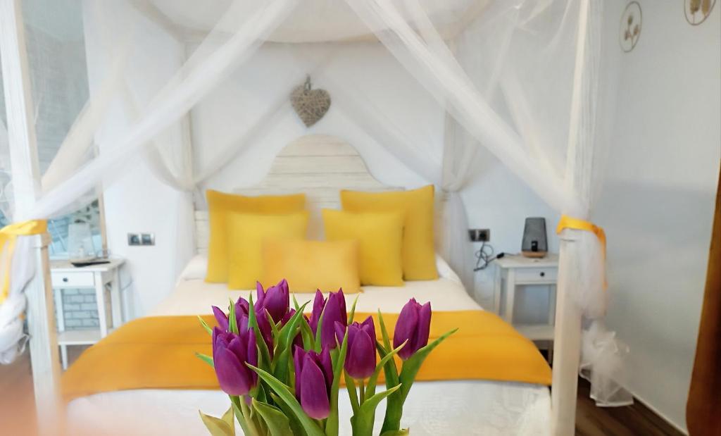 VillamielEscapada Romantica con Jacuzzi y vistas al Castillo de Trevejo的一间卧室配有一张带黄色枕头和紫色鲜花的床。