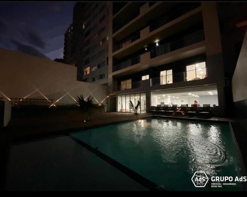 马普托XENON PRIME Urban Apartments的一座游泳池,在晚上在建筑物前