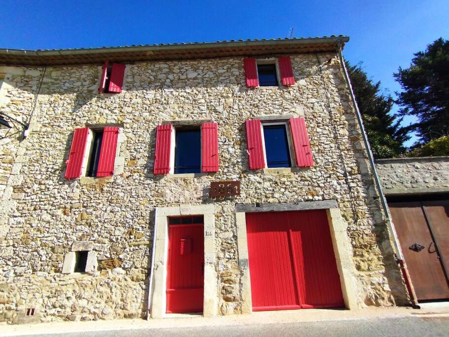欧雷勒Grande Maison Luberon Ventoux的一座石头建筑,上面有红色百叶窗