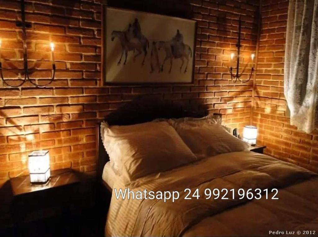 佩尼多Pousada Romântica Serra da Mata的一间卧室设有砖墙和一张带两个灯的床