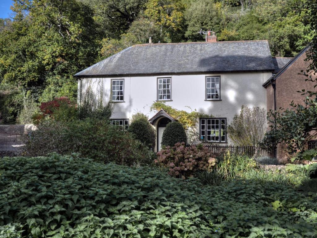 邓斯特Dunster Mill House的花园中一座古老的白色房子