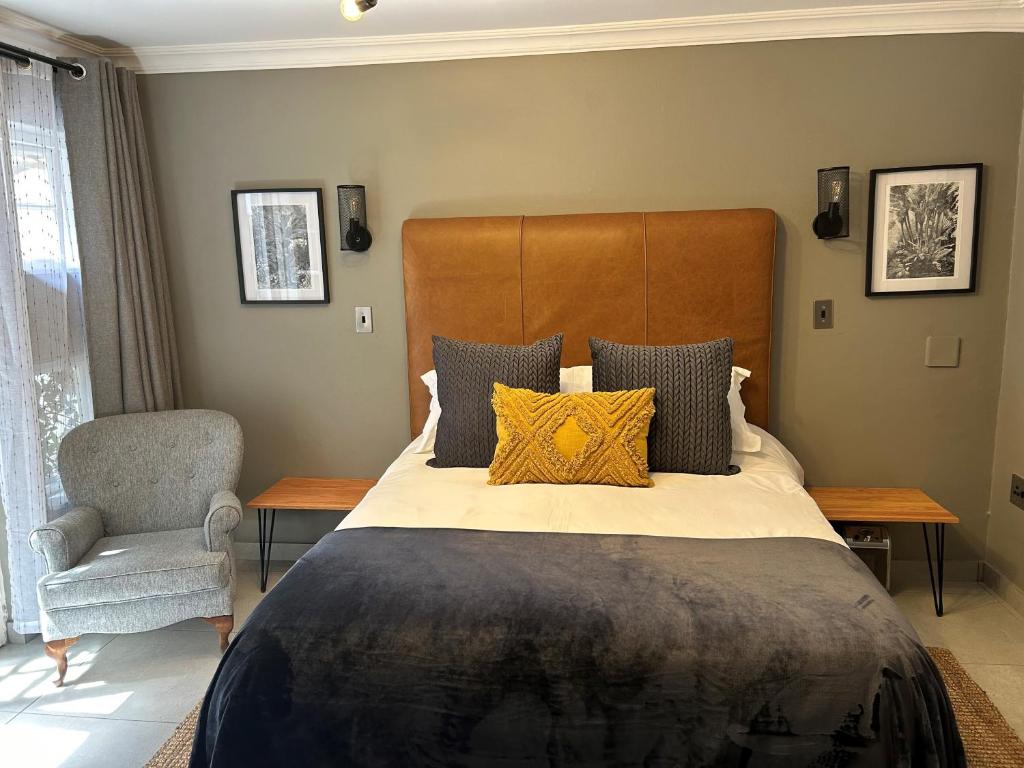 比勒陀利亚Battiss Guest House的一间卧室配有一张大床和一把椅子
