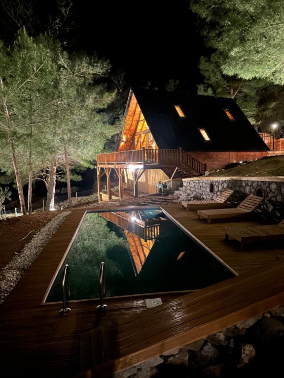 乌尔拉Panurlawoodenhouse özel havuz& sauna mavi的一座晚上设有游泳池的房子