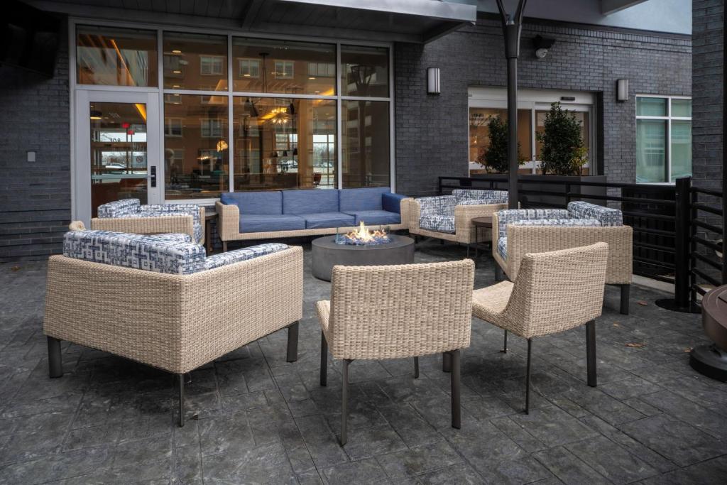 路易斯威尔TownePlace Suites by Marriott Louisville Downtown的庭院设有藤椅和蓝色沙发。