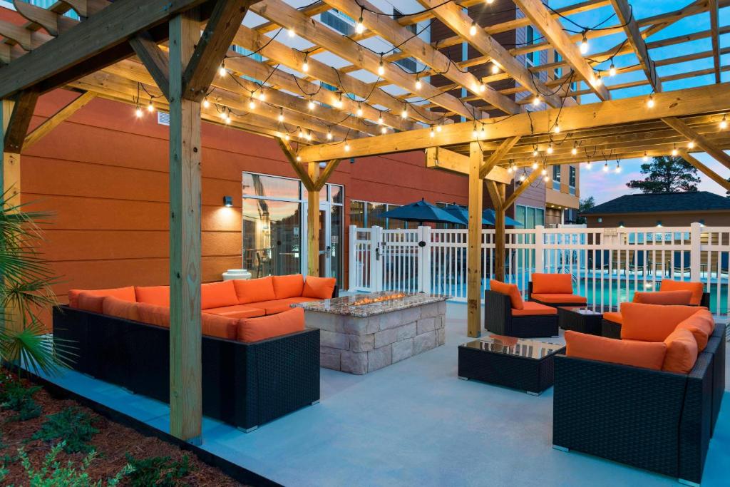 西门罗Fairfield Inn & Suites by Marriott West Monroe的庭院配有橙色椅子和木制凉亭。