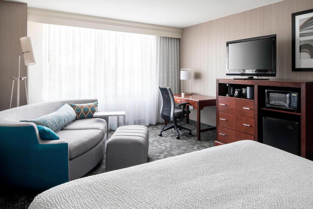 费德勒尔韦Courtyard by Marriott Seattle Federal Way的酒店客房设有一张沙发和一张带电视的书桌。