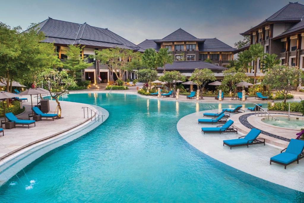 努沙杜瓦巴厘岛努沙杜瓦花园万豪酒店的度假村的游泳池,设有蓝色椅子和建筑