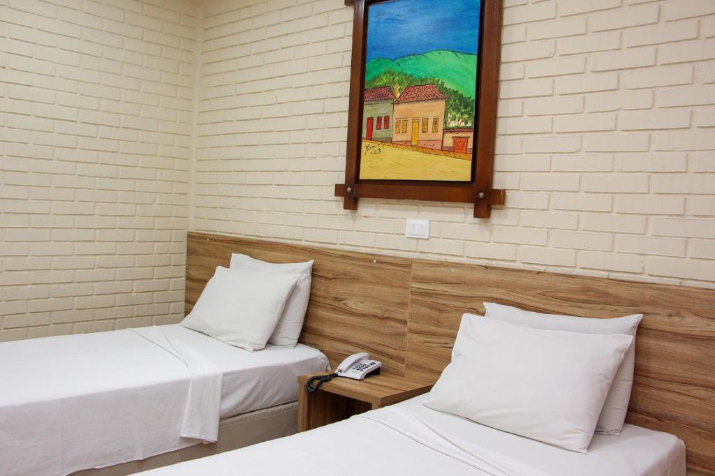 戈亚尼亚Rede Andrade Goiania Centro的一间设有两张床的客房和墙上的镜子