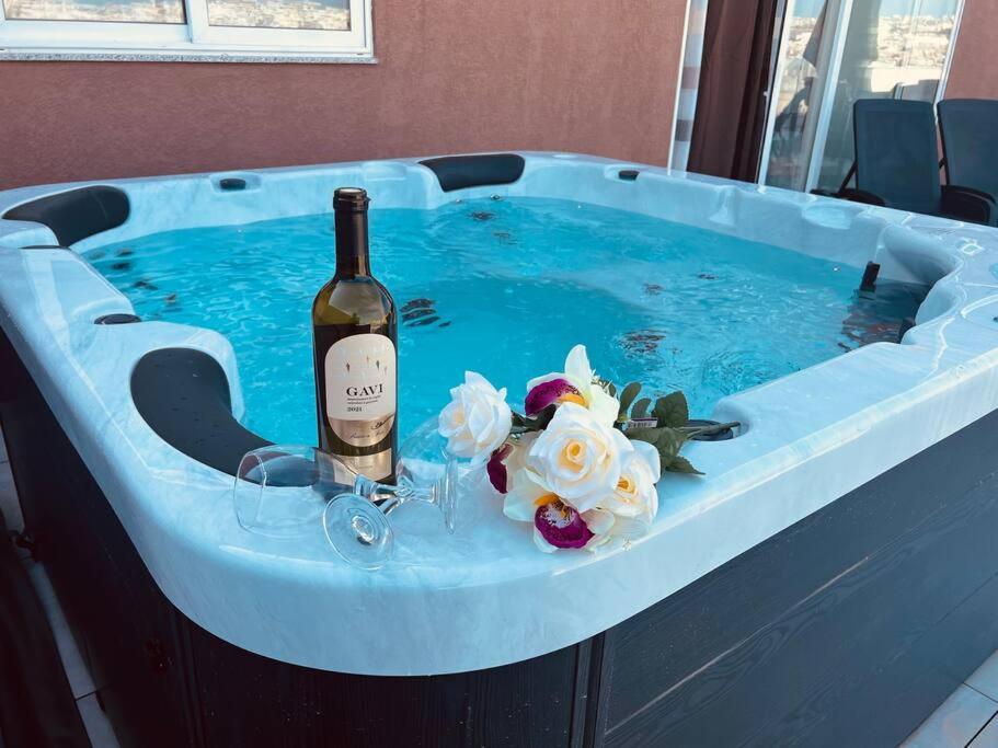 比尔基卡拉The Hazel penthouse with private jacuzzi的热水浴池内的一瓶葡萄酒和鲜花
