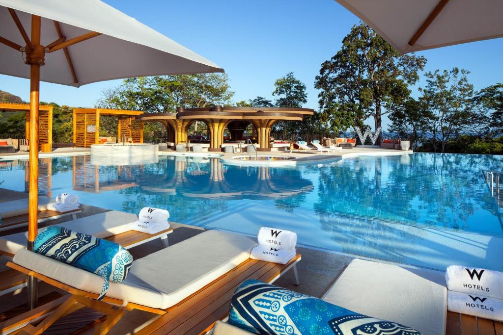 普拉卡海尔W Costa Rica Resort – Playa Conchal的一个带椅子和遮阳伞的游泳池