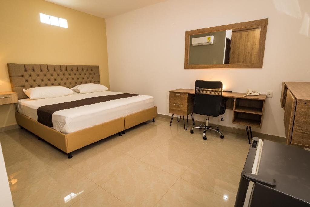 辛塞莱霍Genesis Hotel的一间卧室配有一张床、一张书桌和一面镜子
