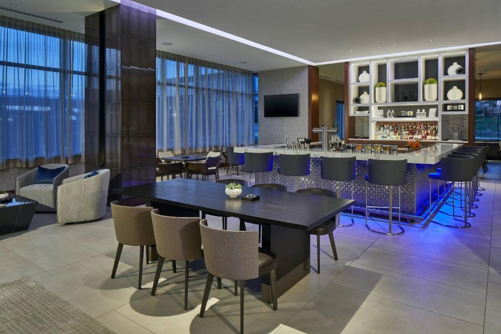 亚特兰大AC Hotel by Marriott Atlanta Airport Gateway的一间带桌椅的用餐室和一间酒吧