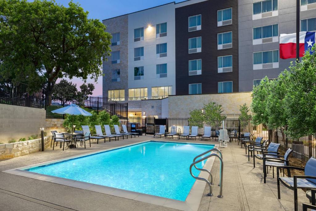奥斯汀TownePlace Suites by Marriott Austin Northwest The Domain Area的一座带桌椅的游泳池以及一座建筑