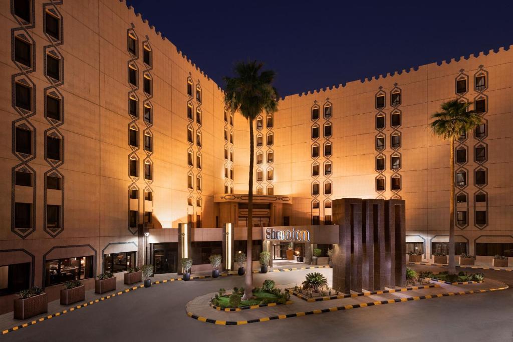 利雅德利雅得喜来登酒店的一座大建筑,前面有棕榈树