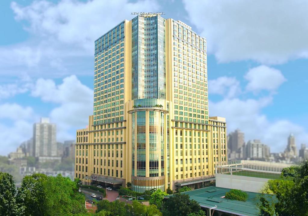 马尼拉New Coast Hotel Manila (formerly New World Manila Bay Hotel)的一座高大的黄色建筑,以城市为背景