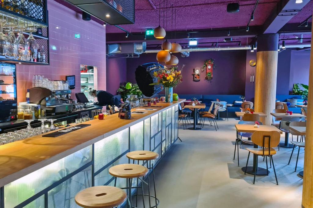 乌得勒支Stayokay Hostel Utrecht Centrum的餐厅内的酒吧,拥有紫色的墙壁和凳子