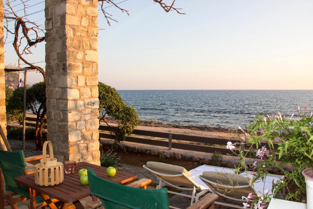 圣尼古拉奥斯Bostani Seaside House Mani的一个带桌椅的庭院和大海
