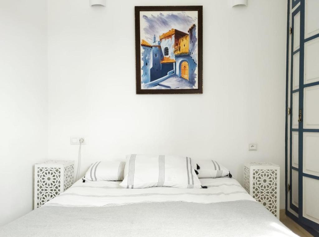 丹吉尔Maison Médina, terrasse panoramique的卧室配有一张床,墙上挂有绘画作品