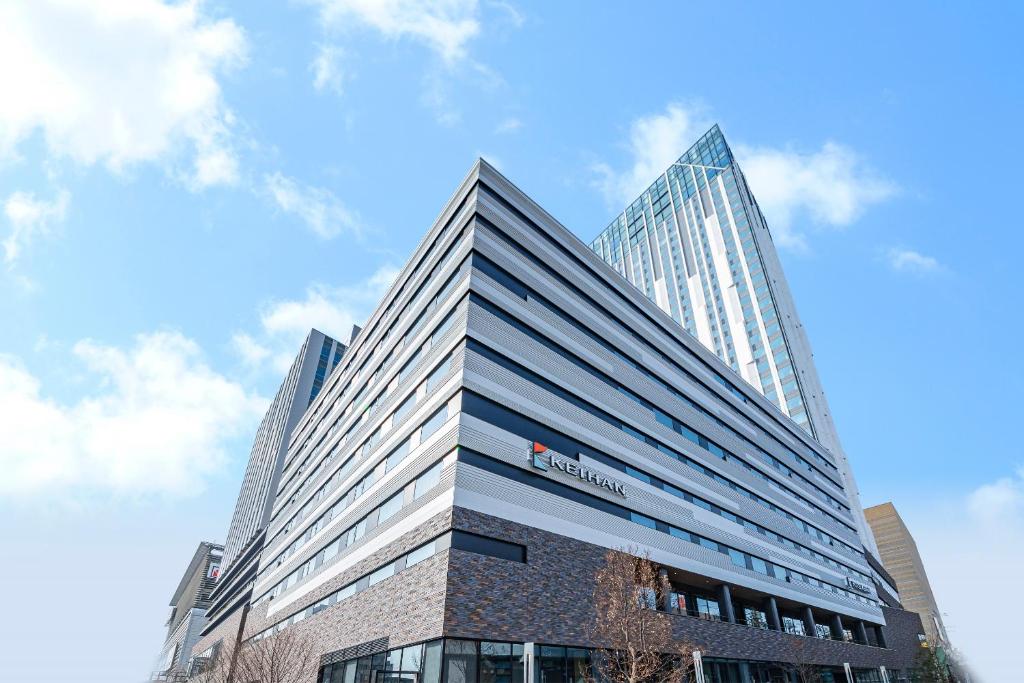 大阪Hotel Keihan Namba Grande的一座高大的建筑,旁边有一个标志