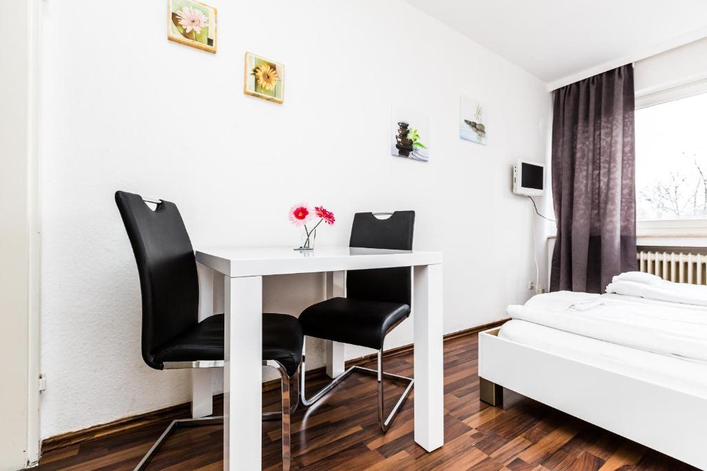 科隆Easy Apartments Work and Stay Cologne的一间设有白色桌子和黑色椅子的客房