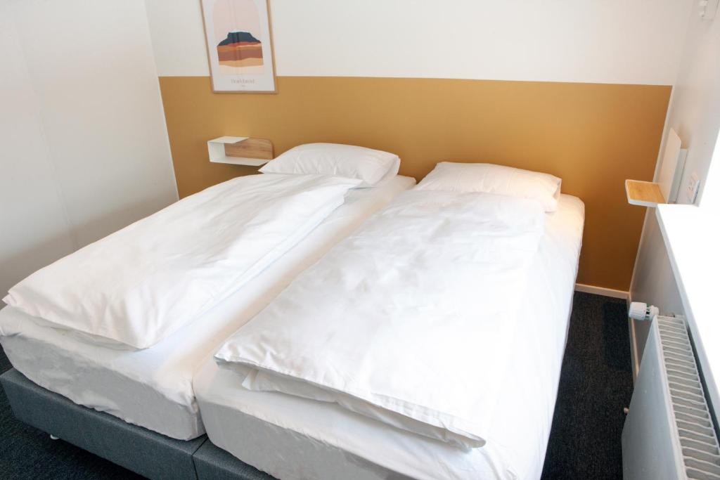 EiðarEiðar - Hostel的配有白色床单和枕头的宿舍间内的一张床位