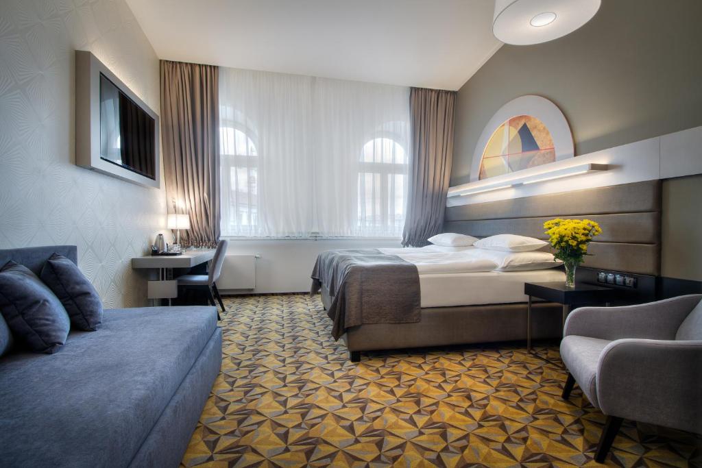 布拉格Hotel Essence的酒店客房,配有床和沙发