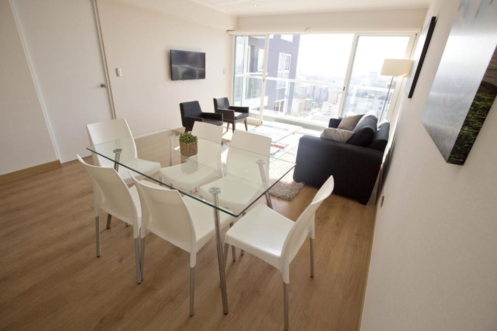利马乌尔巴诺米拉帕尔多公寓的客厅配有玻璃桌和白色椅子
