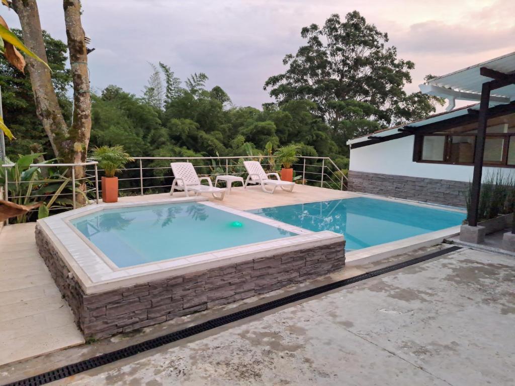 金巴亚Casa de Campo Las Partidas的一个带两把草坪椅的游泳池和一个游泳池