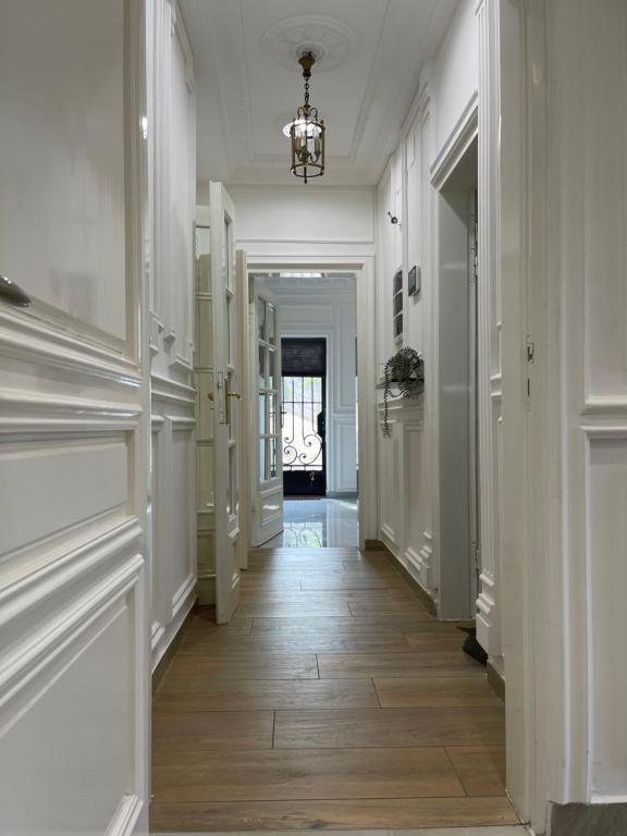 雅温得EVE HOME的走廊设有白色墙壁、木地板和吊灯
