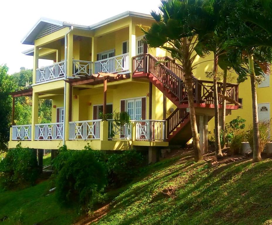 卡斯特里Seascape Villa 3BR with Stunning Caribbean Sea View的黄色房屋,设有阳台和棕榈树