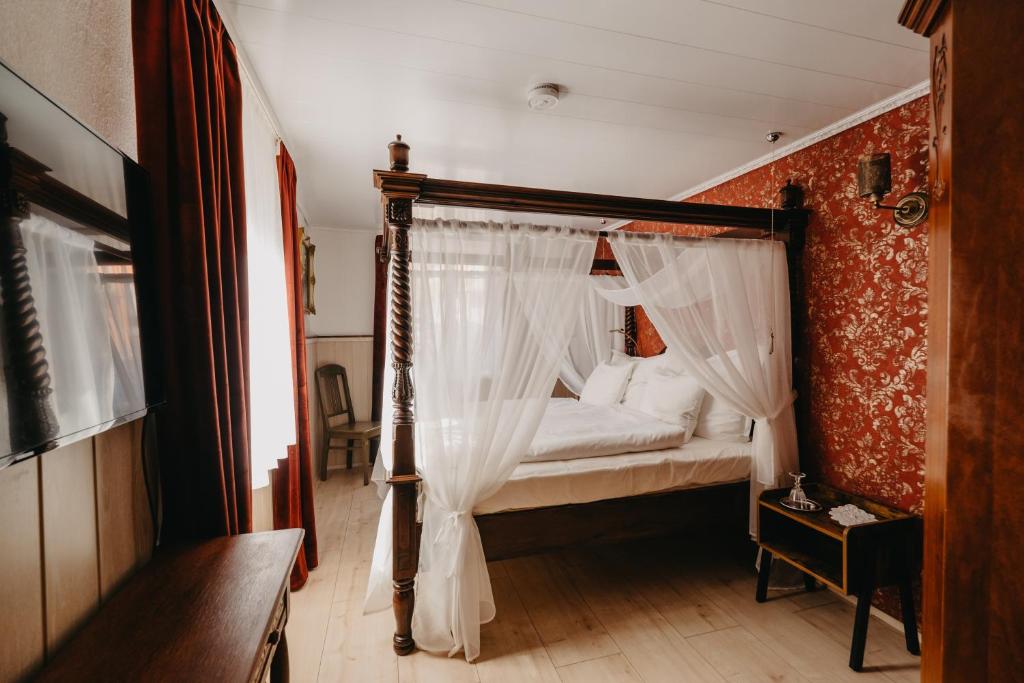 埃登科本Altes Häusle am Waschbach Ferienwohnungen的卧室配有带白色窗帘的天蓬床