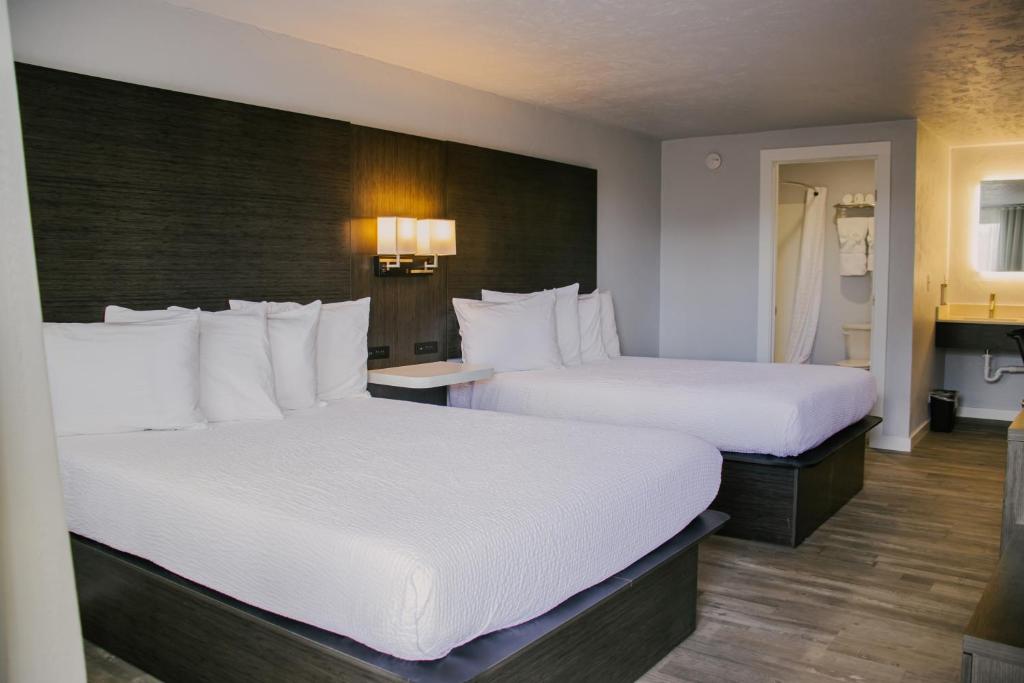 布兰丁Bears Ears Inn的配有白色床单的酒店客房内的两张床