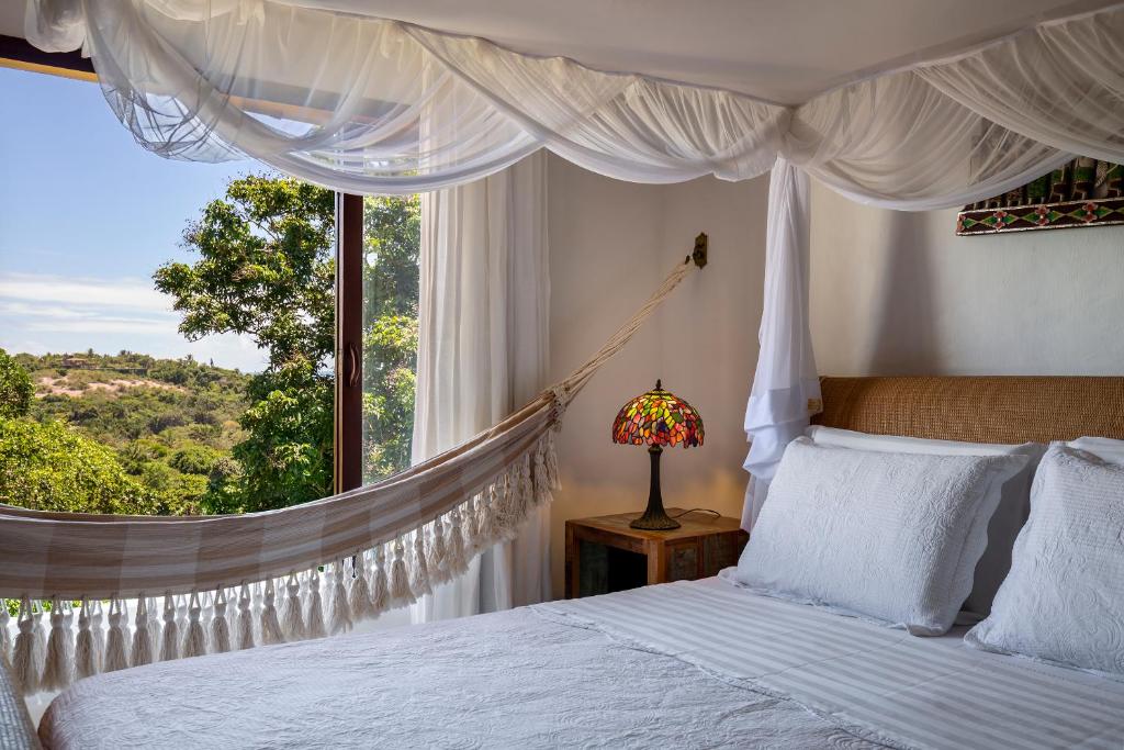 托兰克索Pousada Hospedaria do Quadrado的卧室配有一张床铺,窗户前设有吊床
