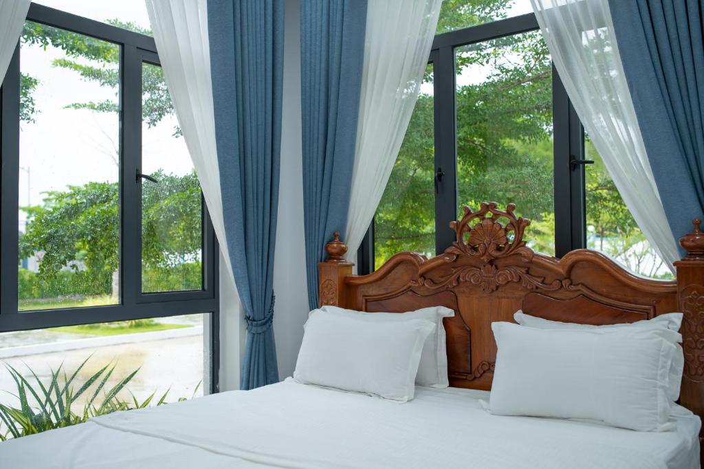 贡布Damnak Borey Resort的配有窗户的客房内的一张带白色床单和枕头的床