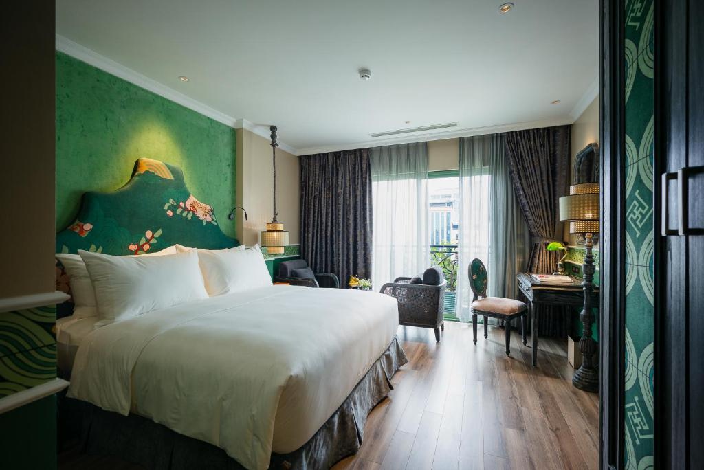 河内Smarana Hanoi Heritage - Hotel and Retreats的酒店客房设有一张大床和一张书桌。