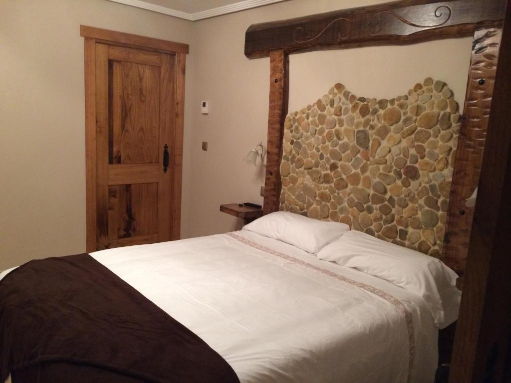 Cereceda埃尔莫利诺日卡达尔索旅馆的一间卧室配有一张大床和木制床头板