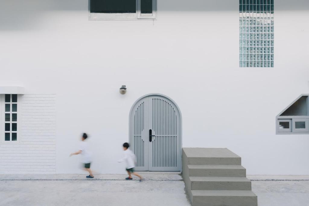 芭东海滩Dokdin's Family的两个人走过一扇门的白色建筑