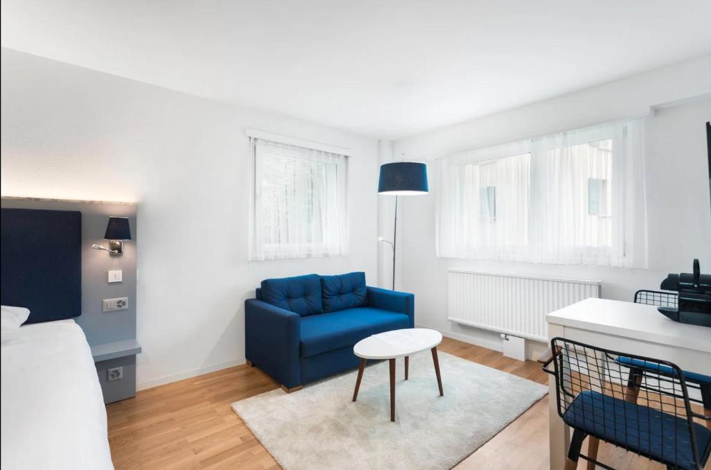 洛桑Sallaz Residence by Homenhancement的客厅配有蓝色的沙发和桌子