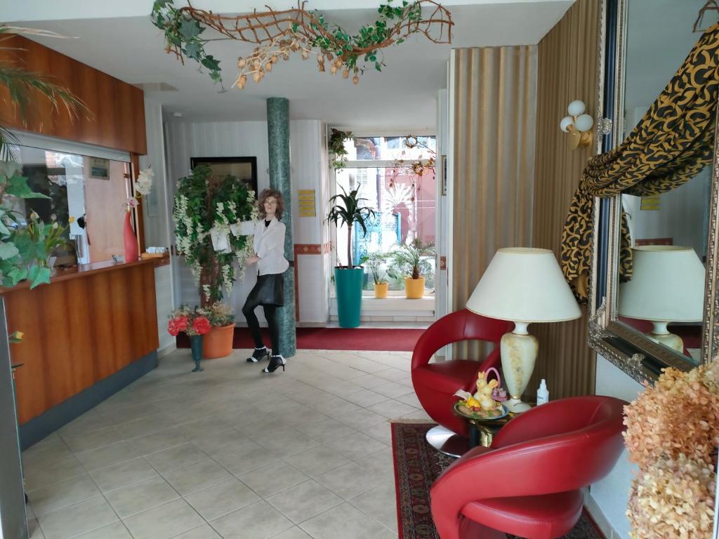 施特雷利茨Hotel Haegert的一位站在走廊上,戴着红椅的女士