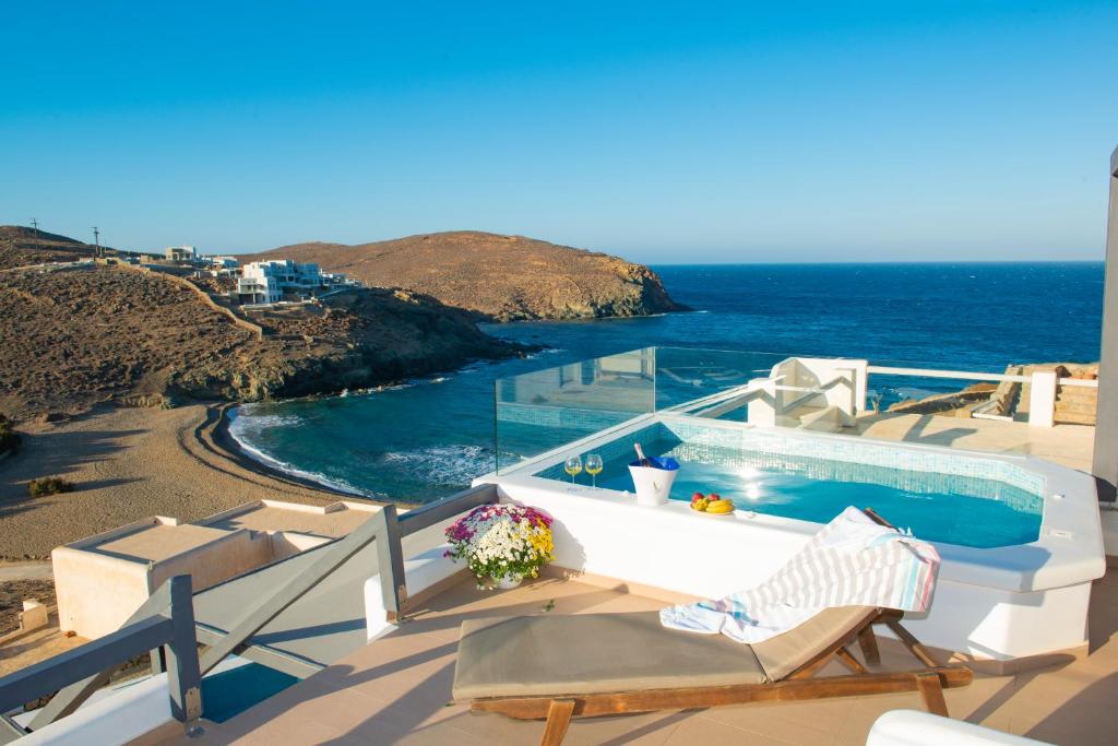 米克诺斯城Myrsini's Luxury Suites Merchia的一个带游泳池和椅子的阳台,享有海景