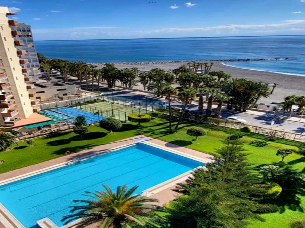 阿尔姆尼卡Apartamento Las Góndolas Playa ALOJAMIENTOS VISTAMAR的享有游泳池和海滩的上方景色