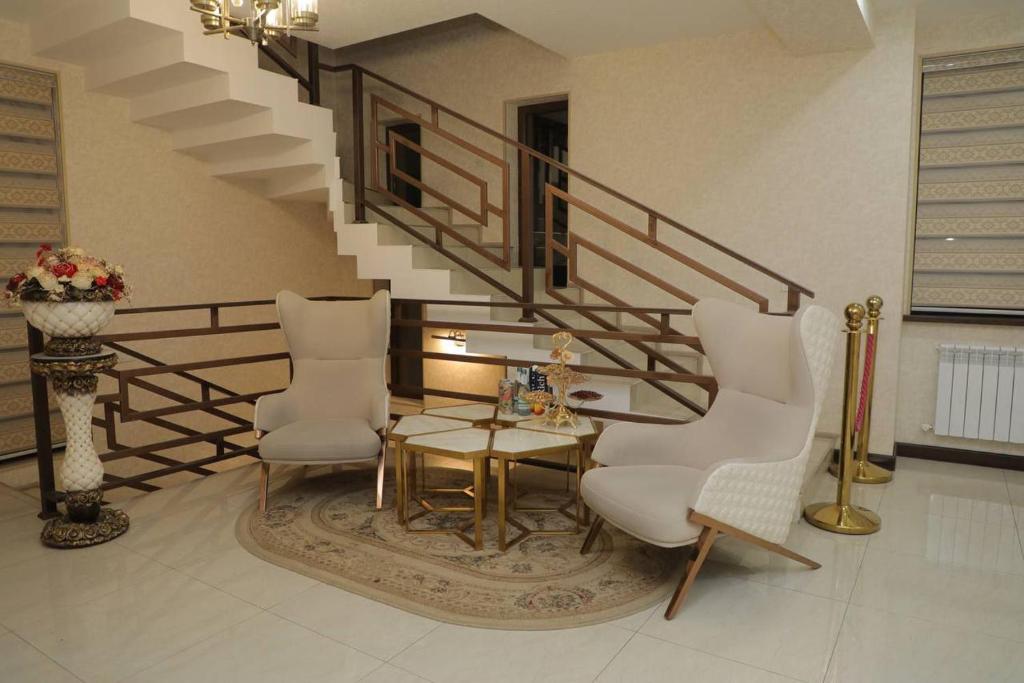 塔什干Premium Hotel 777的客厅配有桌子和两把椅子,设有楼梯